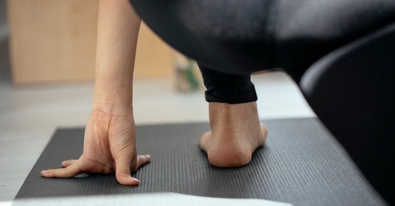 Holistic Wellness - Back view of crop unrecognizable flexible female stretching legs and practicing yoga in Crescent Lunge on the Knee pose at home